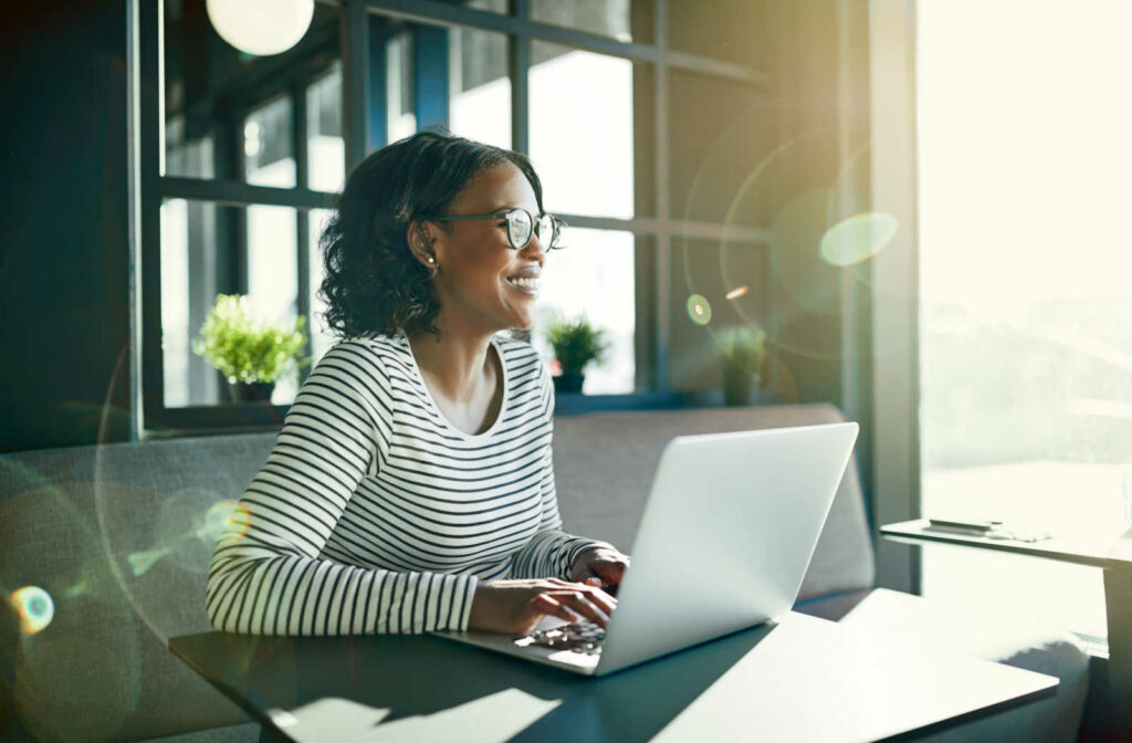 A woman wearing glasses with anti-reflective coating on them to reduce the glare from light sources surrounding her