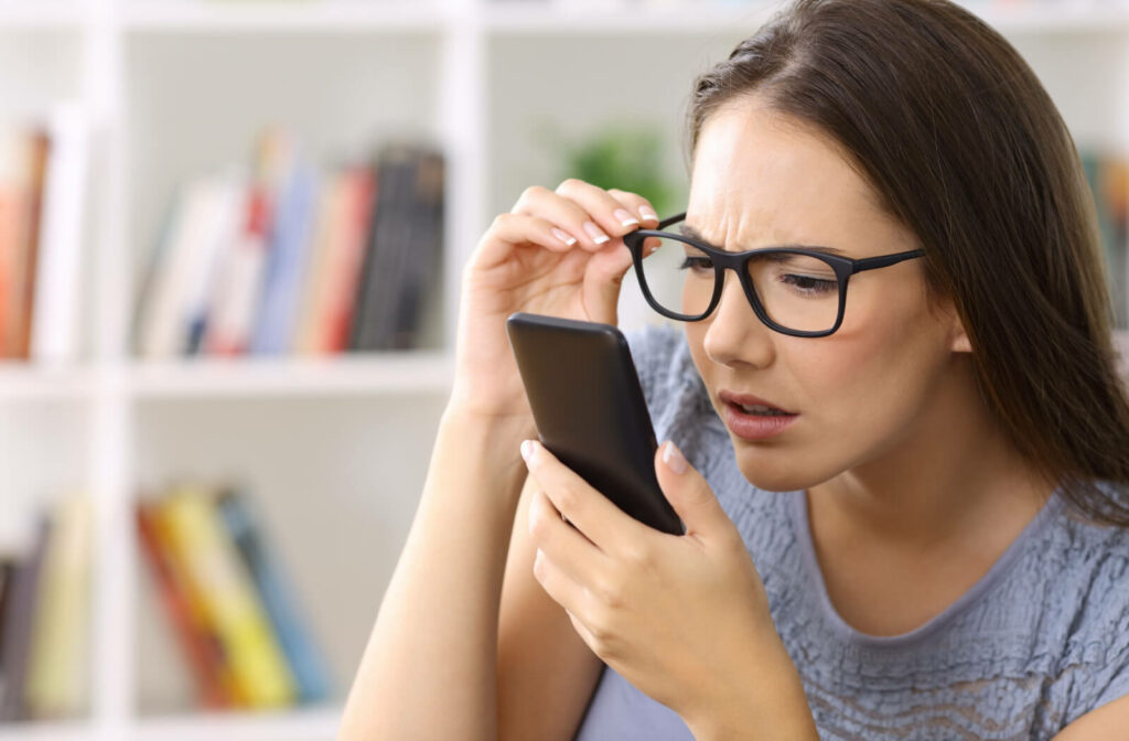 A woman trying to read messages on her phone too close to her face.  Nearsightedness is a common vision condition that causes objects that are far away to appear blurry while objects up close appear clear