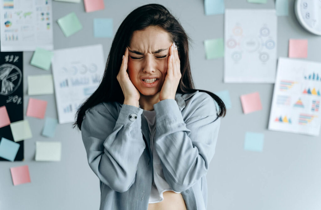 A young female student is massaging her head due to the severe pain she's experiencing from a migraine. Visual disturbances can include yellow spots during migraines