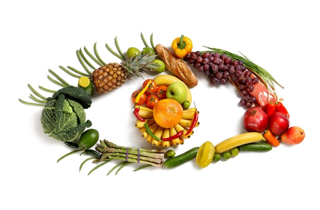 Various fruits, vegetables, meats, fish, and legumes are organized against a white background in the shape of an eye.