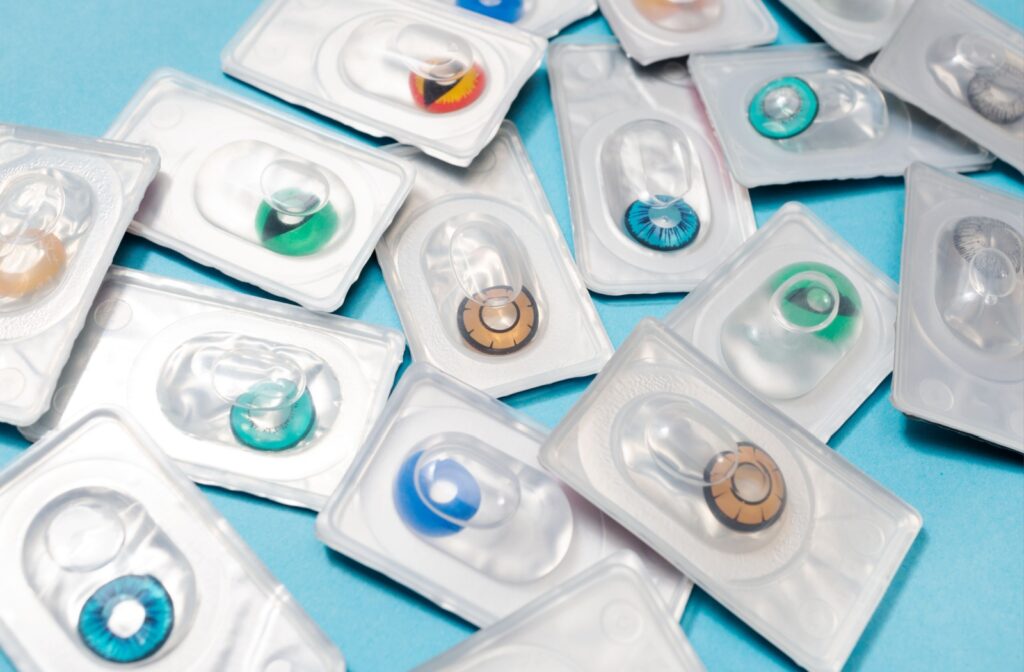 An array of colored contacts in their packaging, scattered across a blue surface.