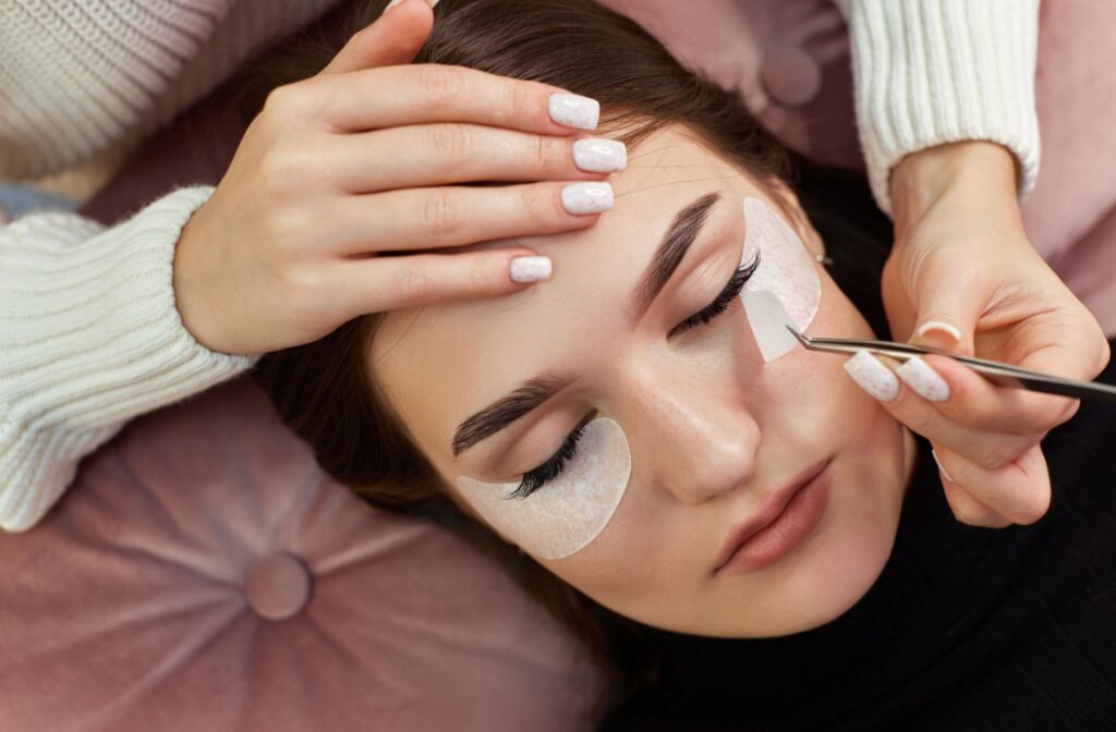 a person getting eyelash extensions applied by an eyelash extension technician