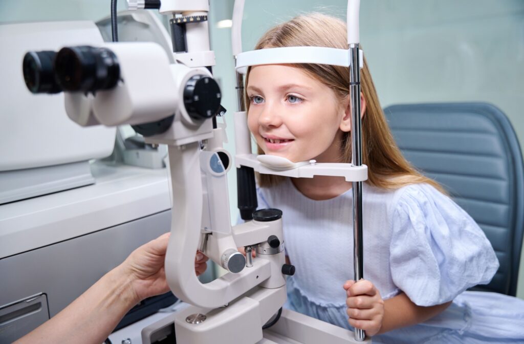 Young patient smiling with head positioned in optometry equipment during a children's eye exam.
