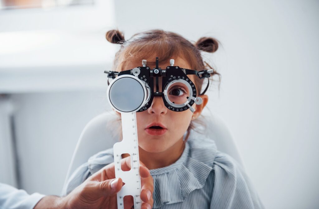 Young patient at an optometry clinic undergoing an eye exam, with one eye covered by a diagnostic tool and the other eye open attentively.