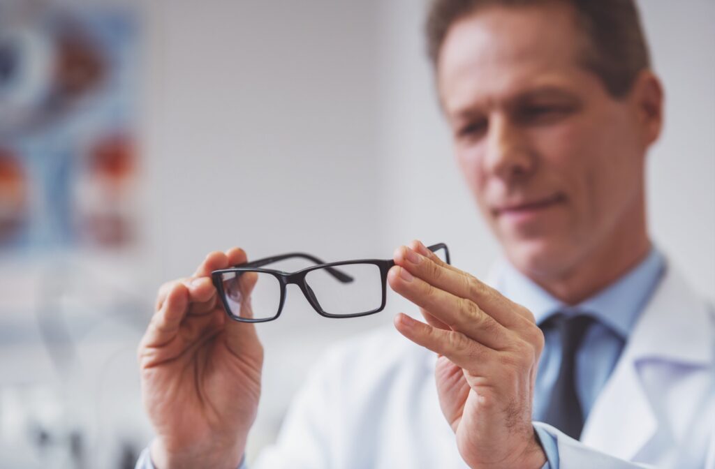 An optometrist holding a pair of glasses that help correct presbyopia.