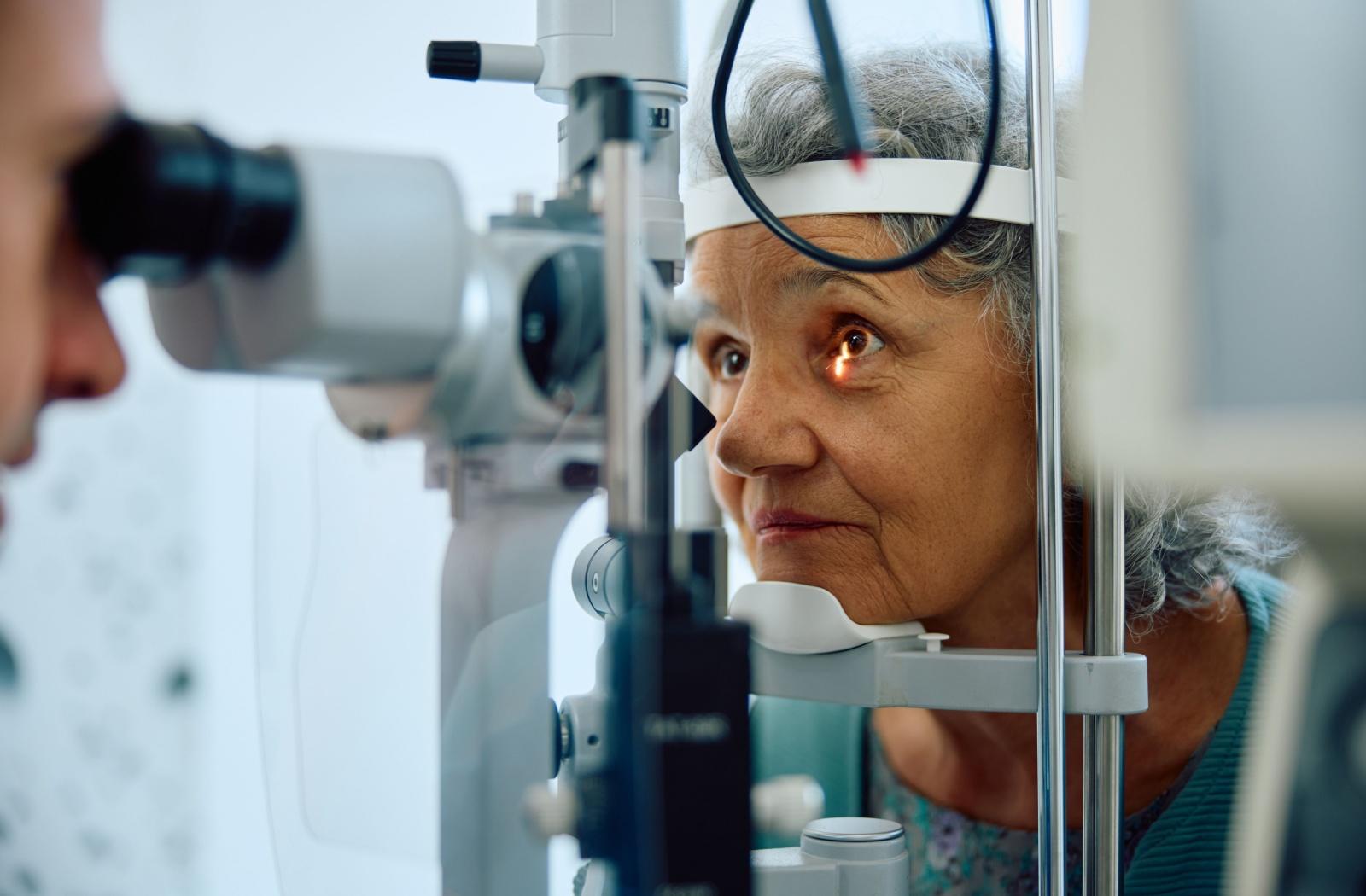 A person having their eyes examined by an optometrist due to noticing signs of having yellow eyes.